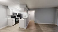 This efficiently designed 1-bedroom, 1-bathroom unit offers a well-organized single-floor layout that maximizes every square foot. The open-concept kitchen and living area form the heart of the unit, where white cabinetry, black appliances — including a range, microwave, and refrigerator — and a peninsula with a built-in sink create a functional and visually clean cooking space. Track lighting above the kitchen and a textured ceiling add character throughout. Light wood-tone vinyl plank flooring runs consistently across the unit, lending warmth and cohesion to the interior. The living area is bright and airy, benefiting from a large sliding glass door with vertical blinds that invites natural light and provides outdoor access. A hallway connects the main living space to the private bedroom, which features a ceiling fan with integrated lighting, a window with blinds, and ample room for furnishings. The bathroom is straightforward and functional, equipped with a full tub-shower combo finished in white tile. Storage is a notable strength of this unit, with three closets, a dedicated pantry, and a laundry area ensuring practical organization throughout. The cool gray wall palette and clean white trim maintain a neutral, move-in-ready aesthetic from room to room.
