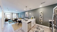Located at 5 Views Lake Dr in Clayton, NC, this well-appointed one-bedroom, one-bathroom residence offers a thoughtfully designed single-floor layout. The open-concept living area seamlessly connects the kitchen, dining, and living spaces, creating an airy and functional environment. The kitchen is a standout feature, showcasing white shaker cabinetry, a striking marble-look quartz island, stainless steel appliances including a refrigerator, electric range, and built-in microwave, along with a subway tile backsplash and sleek pendant lighting. Warm, light-toned luxury vinyl plank flooring runs throughout the main living areas, complemented by bold slate-green accent walls that add depth and modern character. The living room is bright and inviting, with recessed lighting and natural light filtering through large windows. The spacious primary bedroom features plush carpet, a ceiling fan, and ample closet storage. The bathroom is clean and contemporary, with white cabinetry, a quartz vanity top, and wood-look flooring. Additional conveniences include a dedicated laundry room and utility space, making this a complete and practical residence in a desirable Clayton location.