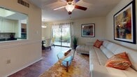 Located at 2481 NE Coachman Rd in Clearwater, Florida, this single-floor residence offers a thoughtfully designed layout that balances comfort and functionality. The open-plan living and dining area serves as the heart of the home, featuring rich hardwood-style flooring, ceiling fans, and a textured ceiling throughout. Large sliding glass doors flood the space with natural light and provide views of the greenery outside, creating a bright and welcoming atmosphere.

The living room is a well-proportioned space anchored by a ceiling fan with a light kit, wainscoting along the lower walls, and ample room for comfortable furnishings. It flows seamlessly into the dining area, which benefits from the same natural light and outdoor views through the sliding glass door access.

The kitchen is efficiently designed with white cabinetry, dark granite-style countertops, stainless steel appliances including a refrigerator and range, a tile backsplash, and light tile flooring. A pass-through window connects the kitchen to the living and dining areas, enhancing the open feel of the home.

The bedroom is a serene retreat featuring plush carpeting, multiple windows dressed with blinds and curtains, and a textured ceiling. The room offers generous space for a full furniture arrangement and is complemented by warm, ambient lighting. Overall, this residence presents a clean, inviting interior suited for comfortable Florida living.