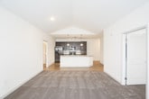 This single-story residence is designed with a thoughtful open layout that seamlessly connects the main living areas. The living room is a standout space, featuring soaring vaulted ceilings, a ceiling fan, a classic fireplace flanked by windows that invite natural light, and plush neutral carpeting throughout. An open doorway connects the living area to additional rooms, enhancing the sense of flow.

The kitchen is well-appointed, showcasing rich dark cabinetry paired with light granite countertops, a subway tile backsplash, and a full suite of black and stainless steel appliances including a refrigerator, range, and built-in microwave. A large peninsula with an integrated sink and pendant lighting above serves as a functional centerpiece, while light wood-tone flooring grounds the space.

The bedrooms are generously sized, each featuring ceiling fans, soft carpeting, and windows fitted with blinds. At least one bedroom includes a spacious walk-in closet outfitted with multi-level shelving and hanging rods. The bathroom offers a dark-stained vanity with white countertops, a tiled tub-shower combination, and wood-tone flooring, maintaining a cohesive design aesthetic throughout the residence.