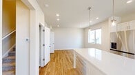 Located in Denver's 80249 neighborhood, this two-story home offers four bedrooms and three bathrooms across two thoughtfully laid-out floors. The main level features an open-concept kitchen and living area finished with warm hardwood-style flooring throughout. The kitchen is a standout, boasting white shaker cabinetry, quartz countertops, a large central island with pendant lighting, stainless steel appliances including a gas range, microwave, refrigerator, and dishwasher, plus a window above the sink that fills the space with natural light. The living and dining areas flow seamlessly from the kitchen, providing an airy, connected feel ideal for everyday living and entertaining. Upstairs, the upper level houses the bedrooms, which are finished with plush carpeting for added comfort. The primary bedroom is generously sized, featuring a ceiling fan and a large window with neighborhood views. Secondary bedrooms include built-in closets and bright windows. The bathrooms are clean and modern, with white subway tile tub-shower surrounds, quartz vanities, and hardwood-style tile flooring. A hallway and two staircases connect the levels efficiently, completing this well-appointed Denver home.