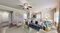 This single-story, 3-bedroom, 3-bathroom residence offers a thoughtfully designed layout that balances comfort and functionality. A welcoming hallway with hardwood-style flooring and crown molding leads into the heart of the home. The open-concept living, dining, and kitchen area serves as the central gathering space, featuring ceiling fans, crown molding, and abundant natural light from large windows and French doors. The living room accommodates generous seating and is anchored by a wall-mounted TV and access to an outdoor area. The kitchen is equipped with stainless steel appliances, warm wood cabinetry, and granite-style countertops, flowing seamlessly into a bright dining nook with a large window overlooking the outdoors. Each of the three bedrooms offers carpeted flooring and ample natural light, with the primary bedroom featuring an en-suite bathroom complete with a double vanity, granite countertops, and direct access to a spacious walk-in closet with wire shelving systems. The additional bedrooms are well-sized and versatile. Three full bathrooms ensure convenience for all occupants. A dedicated in-unit laundry room with side-by-side washer and dryer adds everyday practicality. The home's neutral palette and consistent finishes create a cohesive and inviting ambiance throughout.