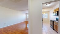 Located at 1 Chester Cir in New Brunswick, NJ, this one-bedroom, one-bathroom unit offers a practical and well-organized single-floor layout. Gleaming hardwood floors flow throughout the living room, dining room, and bedroom, lending warmth and continuity to the space. The living room is generously sized, featuring baseboard heating and natural light from windows, creating a bright and comfortable area for everyday living. Adjacent to the living room, the dining area is accented by a chandelier overhead and connects seamlessly to the kitchen. The galley-style kitchen is equipped with black appliances including a refrigerator, electric range, and microwave, complemented by warm wood cabinetry and light tile flooring that extends underfoot. A hallway leads to the spacious primary bedroom, which features polished hardwood floors, a closet, and ample room for furnishings. The full bathroom is finished with neutral tile throughout, including a tiled tub-and-shower combination with a decorative mosaic accent strip, a wood-cabinet vanity with a white countertop, and a small window for ventilation. Three closets distributed throughout the unit provide excellent storage. The clean, neutral palette and functional layout make this a well-rounded residential space.