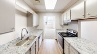 This urban residence at 165 N Water Street in Rochester, NY offers a blend of comfort and contemporary design across its 1,160 square feet. The apartment boasts three bedrooms, including an exceptionally large primary bedroom measuring 530 square feet. The open-concept layout is enhanced by large windows that flood the space with natural light, offering views of the surrounding cityscape.

The modern kitchen is a standout feature, equipped with sleek white cabinetry, granite countertops, and stainless steel appliances. The galley-style layout maximizes efficiency while providing ample storage and preparation space. Wood-look flooring in the kitchen adds warmth and contrast to the crisp, white aesthetic.

The bathroom is clean and functional, featuring a white tub-shower combination, toilet, and simple fixtures. The bedrooms are carpeted for comfort and showcase the apartment's abundance of natural light. Track lighting in the main living areas adds a contemporary touch and allows for customizable illumination.

Throughout the apartment, neutral-toned walls and carpeting create a blank canvas for personalization. The drop ceiling in some areas suggests a converted or renovated space, adding character to this urban dwelling. With its spacious layout and modern amenities, this apartment offers a comfortable and stylish living experience in the heart of Rochester.