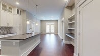 This contemporary 980 square foot residence offers a thoughtful blend of form and function. The single-story layout encompasses two bedrooms, including a primary suite of 150 square feet, and three full bathrooms, providing ample personal space and convenience. The heart of the home is an open-concept kitchen and living area, characterized by rich, warm-toned hardwood flooring that extends throughout, creating a seamless flow and visual continuity.

Recessed lighting adorns the ceiling, offering adjustable illumination to suit various moods and activities. A standout feature is the custom built-in shelving, which not only provides practical storage solutions but also adds architectural interest to the space. The neutral wall color serves as a versatile backdrop, ready to complement any decor style.

The efficient floor plan makes the most of the available square footage, with a hallway connecting the various rooms and two closets offering additional storage. The kitchen area, while not fully visible in the image, appears to be integrated into the main living space, promoting a social atmosphere ideal for entertaining or family gatherings. Overall, this residence strikes a balance between compact living and comfortable, well-appointed spaces.