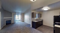 This single-floor residence offers a thoughtfully designed open-concept layout that seamlessly connects the living area and kitchen. The living room features plush carpeting and vaulted ceilings that lend a sense of spaciousness, with a sliding glass door opening to a private balcony that brings in abundant natural light and outdoor views. The kitchen is well-equipped with dark cabinetry, light quartz-style countertops, a mosaic tile backsplash, a double-basin sink, and a full suite of black appliances including a gas range, microwave, dishwasher, and refrigerator. Wood-look flooring runs throughout the kitchen, providing a clean contrast to the carpeted living spaces. The bedroom is generously sized, featuring soft carpeting, a ceiling fan with light fixture, and a window that allows natural light to filter in. The bathroom is finished with modern touches, including a dark wood vanity, white countertop, large wall mirror with overhead lighting, chrome fixtures, and wood-look flooring. Throughout the residence, a neutral color palette and clean lines create a calm and inviting ambiance, while multiple doors provide convenient access and privacy between living areas.