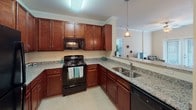 This single-floor residence offers a thoughtfully designed layout that seamlessly connects the living, dining, and kitchen areas into a cohesive open-concept space. The living room is bright and inviting, featuring crown molding, a ceiling fan, and French doors that open to the outdoors, allowing natural light to fill the room. Decorative columns elegantly define the transition between the living and dining areas, adding an architectural touch to the interior.

The kitchen is well-equipped and functional, showcasing rich cherry wood cabinetry, granite countertops, a full suite of black appliances including a gas range and dishwasher, and a convenient breakfast bar that connects to the main living space. A pendant light above the bar adds a warm, welcoming ambiance.

The dining area features crown molding and a classic chandelier overhead, creating an intimate setting for meals. Both bedrooms are comfortably sized with plush carpeting and ample natural light from large windows with blinds. The primary bedroom offers generous space for furnishings, while the second bedroom is equally comfortable.

Each bathroom is finished with granite-topped cherry vanities and full tub-shower combinations. Throughout the home, neutral tones, crown molding, and consistent finishes contribute to a cohesive and polished aesthetic.