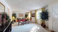 This two-floor residence in Decatur, Georgia, offers a well-organized layout across two levels. The living room is a generously sized, carpet-floored space illuminated by multiple windows dressed in gold-toned curtains that invite natural light. Neutral walls and a textured ceiling complement the open, comfortable atmosphere of the room.

The dining area features warm wood-look flooring and connects smoothly to the kitchen, which is outfitted with white cabinetry, light-toned countertops, a built-in range, dishwasher, and a window above the sink that adds brightness to the workspace.

The primary bedroom is a spacious, carpet-floored retreat with neutral walls and ample room for substantial furnishings. A second bedroom features vibrant window treatments and carpet flooring, offering a lively, adaptable space.

The bathrooms include one with an extended vanity, white cabinetry, wood-look tile flooring, and framed wall art, while a second bathroom features a tub-shower combination. Throughout the residence, consistent use of wood-look flooring in utility areas and plush carpet in living and sleeping spaces creates a cohesive and practical interior.