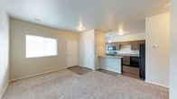 This 2-floor space offers a practical and modern layout with an open-concept main living area that seamlessly connects the living room and kitchen. The living room features neutral-toned carpet, light gray walls, and a window that allows natural light to fill the space, creating a bright and welcoming atmosphere. A flush-mount ceiling light provides additional illumination.

The kitchen is positioned adjacent to the living area and is defined by a raised breakfast bar that serves as a natural divider between the two spaces. Dark espresso cabinetry lines the kitchen walls, complemented by a stainless steel range and microwave, a dark dishwasher, and a sink along the back wall. Pendant lighting hangs above the breakfast bar, adding a refined touch to the functional cooking space.

Dark wood-style flooring runs through the kitchen and entry areas, providing a clean contrast to the carpeted living room. A closet near the entryway offers convenient storage, and a white-paneled entry door completes the main level. The overall design balances practicality with contemporary style, making efficient use of the available space across both floors.