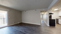 This single-floor residence presents a cohesive, neutral aesthetic throughout its well-organized layout. The main living area is generously proportioned, featuring dark hardwood-style plank flooring that extends through the common spaces, complemented by warm greige walls and crisp white baseboards. A textured popcorn ceiling adds character overhead, while multiple HVAC vents ensure year-round comfort. A sliding glass door opens directly onto a private balcony, introducing natural light and outdoor views into the living space.

The kitchen is efficiently designed with a galley-style configuration, offering white cabinetry, granite-look countertops, black appliances including a range and refrigerator, and a single-basin sink. The layout maximizes storage and workflow within a compact footprint.

The bedrooms are carpeted in a neutral beige tone, each featuring windows with blinds that allow natural light while maintaining privacy. The primary bedroom includes access to a dedicated bathroom with a stand-up shower and a walk-in closet. A secondary full bathroom serves the remaining rooms, fitted with a tub-shower combination, wood-look vinyl flooring, white cabinetry, and granite-look countertops. A hallway connects all areas of the unit seamlessly.