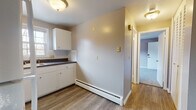 Located at 12 Colonial Ct in Plainville, Connecticut, this single-floor unit offers a practical and comfortable layout throughout. The kitchen is well-equipped with white cabinetry, dark countertops, a tiled backsplash, and white appliances including a refrigerator and electric range. A window above the sink brings in natural light, while wood-look vinyl flooring adds a clean, durable finish to the space. Baseboard heating is present throughout the unit, ensuring warmth during New England winters. The bedrooms are carpeted in neutral grey tones and feature built-in closets for ample storage. One bedroom is enhanced by a ceiling fan and a window overlooking greenery outside, while another features a standard reach-in closet with a hinged door. The bathroom includes a tub-shower combination with white tile surround, wood-look vinyl flooring, warm wood-toned cabinetry, and a window that provides natural ventilation. The overall color palette throughout the unit is neutral and understated, with taupe and grey tones creating a calm, move-in-ready atmosphere. The unit's straightforward single-floor plan makes it accessible and easy to navigate.