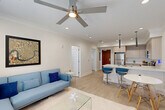 Located at 4650 Washington Ave in New Orleans, LA, this modern one-bedroom, one-bathroom unit offers a thoughtfully designed open-concept layout with clean lines and contemporary finishes throughout. Light wood-style flooring runs continuously through the space, complemented by crisp white walls, crown molding, and recessed lighting that create a bright, cohesive ambiance. The living area is anchored by large windows with blinds that invite natural light, and a ceiling fan overhead adds comfort. The kitchen is a standout feature, boasting light wood cabinetry, white quartz countertops, a central island with a double sink and bar seating, stainless steel appliances, and sleek pendant lights above. The dining area flows seamlessly from the kitchen and living room, making the space ideal for entertaining. The generously sized bedroom features its own ceiling fan, a large window with outdoor views, and ample room for a full furniture arrangement. A dedicated closet provides convenient storage. The bathroom is well-appointed with a wood-toned vanity, white quartz countertop, a tub-shower combination with white subway tile surround, and wood-look tile flooring. A hallway connects all areas efficiently, completing this well-planned New Orleans residence.