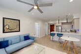 Located at 4650 Washington Ave in New Orleans, LA, this modern one-bedroom, one-bathroom unit offers a thoughtfully designed open-concept layout with clean lines and contemporary finishes throughout. Light wood-style flooring runs continuously through the space, complemented by crisp white walls, crown molding, and recessed lighting that create a bright, cohesive ambiance. The living area is anchored by large windows with blinds that invite natural light, and a ceiling fan overhead adds comfort. The kitchen is a standout feature, boasting light wood cabinetry, white quartz countertops, a central island with a double sink and bar seating, stainless steel appliances, and sleek pendant lights above. The dining area flows seamlessly from the kitchen and living room, making the space ideal for entertaining. The generously sized bedroom features its own ceiling fan, a large window with outdoor views, and ample room for a full furniture arrangement. A dedicated closet provides convenient storage. The bathroom is well-appointed with a wood-toned vanity, white quartz countertop, a tub-shower combination with white subway tile surround, and wood-look tile flooring. A hallway connects all areas efficiently, completing this well-planned New Orleans residence.