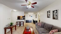 Located on Kecoughtan Road in Hampton, Virginia, this single-floor residence offers a well-organized layout connecting living, dining, and kitchen areas in a cohesive open flow. The living room serves as the centerpiece of the home, featuring a wood-burning fireplace framed by a mirror accent above the mantle, a ceiling fan with integrated lighting, and plush wall-to-wall carpeting. Sliding glass doors provide direct access to the outdoors while allowing natural light to fill the space. A dedicated area adjacent to the living room accommodates a desk and storage dresser, offering functional workspace.

The kitchen is designed in a galley style with light wood cabinetry, dark countertops, tile flooring, and black appliances including a refrigerator, electric range, and microwave. A peninsula counter with bar stool seating connects the kitchen to the main living area, making it ideal for casual dining or entertaining. The entryway transitions seamlessly from the front door into this kitchen-facing space.

The bedroom is generously proportioned, featuring soft carpeting, vertical blinds on the windows, and ample room for a full dresser and nightstands. Textured ceilings are consistent throughout the home, contributing to its classic residential character. The overall ambiance is comfortable and functional, well-suited for everyday living.