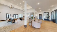 Located at 411 Sage Rd N in White House, Tennessee, this single-story community space offers a generously sized, open-concept layout designed for both comfort and function. The interior is defined by dramatically soaring ceilings that amplify the sense of openness throughout, while recessed lighting and carefully placed pendant chandeliers—including a striking orb-style fixture—provide warm, layered illumination across the space.

Light hardwood flooring extends through much of the area, complemented by large area rugs that delineate distinct seating and activity zones. A welcoming lounge area features plush, neutral-toned sofas and armchairs arranged around a stone-clad fireplace, adding a refined focal point. Adjacent to this is a sizable dining area with a dark rectangular table, woven-back chairs, and sculptural ceramic vessels as décor accents.

Black-framed glass partitions separate a private meeting or office suite, which benefits from its own natural light. A dedicated game area with a billiards table, a beverage station near the entrance, and multiple seating vignettes throughout round out the layout. Large exterior-facing doors and windows invite natural light throughout, contributing to the bright, airy, and welcoming ambiance of the overall space.