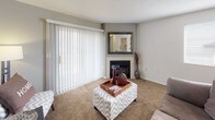 This two-floor residence offers a functional and comfortable layout across both levels. The main floor centers around a carpeted living room highlighted by a fireplace and large sliding glass doors fitted with vertical blinds, allowing generous natural light and outdoor views. The kitchen is well-equipped with white cabinetry, a double-basin sink, a dishwasher, an electric range with overhead microwave, a full-size refrigerator, and stone-look tile flooring throughout. A dining area sits adjacent to the kitchen, providing a convenient everyday eating space. The main-floor primary bedroom features warm grey accent walls, soft carpet, and ample space for a full bedroom suite. A full bathroom on this level includes a single-vanity with white cabinetry, a shower-tub combination, and stone-look tile flooring. An additional bathroom on the main floor provides a toilet, vanity, and access to a walk-in closet. The lower level houses two additional bedrooms, each carpeted and uniquely styled — one with neutral tones and the other with lavender accent walls — both offering comfortable, private retreats. Throughout the home, carpet and tile flooring are used purposefully, and the overall layout is designed to maximize livability and practicality across both floors.