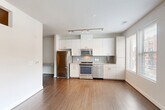Located at 455 S Maple Ave in Falls Church, Virginia, this well-appointed one-bedroom, one-bathroom residence offers a clean, modern aesthetic throughout its thoughtfully designed single-floor layout. The open-concept kitchen and living area serves as the heart of the home, featuring rich hardwood flooring, crisp white cabinetry extending to the ceiling, granite countertops, a subway tile backsplash, and a full suite of stainless steel appliances including a refrigerator, range, microwave, and dishwasher. Track lighting overhead enhances the kitchen's functionality, while large windows invite abundant natural light and offer views of the surrounding streetscape. The spacious bedroom is finished with plush carpeting, a high horizontal window for additional light, and direct sightlines to the kitchen. Two closets provide generous storage, complemented by an in-unit laundry area for added convenience. The full bathroom is tastefully appointed with tile flooring, a soaking tub with subway tile surround, a dark-toned vanity with granite countertop, an overhead medicine cabinet, and a well-lit mirror. A clean corridor connects the living spaces, maintaining a cohesive and efficient flow throughout the residence. The overall ambiance is bright, contemporary, and move-in ready.