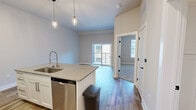 Located at 661 Wedgewood Ave, Unit 613 in Nashville, TN, this efficiently designed 550-square-foot, one-bedroom, one-bathroom apartment offers a thoughtful layout across a single floor. The open-concept living and kitchen area is anchored by a granite-topped kitchen island with a built-in sink and pendant lighting overhead. The kitchen features white shaker cabinetry, granite countertops, and a full suite of stainless steel appliances including a refrigerator, electric range, microwave, and dishwasher. Wood-look flooring runs throughout the main living areas, adding warmth and continuity to the space. The 150-square-foot bedroom is carpeted for comfort and includes a ceiling fan, a natural light-providing window with blinds, and direct access to a spacious walk-in closet outfitted with multi-level wire shelving for ample storage. The bathroom continues the home's clean aesthetic with white cabinetry, granite countertops, and wood-look flooring. Neutral gray and beige tones throughout the apartment create a cohesive, modern ambiance, while recessed lighting in the main living area enhances the bright, open feel of this well-appointed Nashville residence.