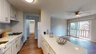 Located at 13461 Community Rd in Poway, California, this single-floor residence offers a well-organized layout with thoughtfully designed living spaces throughout. The kitchen is a standout feature, showcasing white shaker-style cabinetry, quartz countertops, a gas range, and a central island with beadboard paneling — all finished in a crisp, clean palette. Warm wood-tone flooring runs through the kitchen and living areas, lending a cohesive and inviting feel. The living room is generously proportioned, bathed in natural light through large sliding glass doors that open to an outdoor balcony, and is equipped with a ceiling fan for added comfort. A wall-mounted HVAC unit provides additional climate control. The bedrooms feature soft carpeting, ceiling fans, and ample closet space, creating comfortable, functional retreats. Windows in the bedrooms allow for natural light and outdoor views. The bathroom is well-appointed with a quartz vanity, a full tub-shower combination with tiled surround, and a large mirror. Neutral gray tones on the walls throughout the residence create a calm, versatile backdrop, making the space move-in ready and easy to personalize.