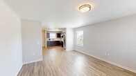 This two-story home in Highland, Illinois offers a well-organized layout across two floors, totaling just under 1,000 square feet of living space. The main level houses the kitchen and living room, connected by a hallway and staircase. The kitchen is a standout feature, equipped with rich dark cabinetry, light countertops, stainless steel appliances including a gas range and refrigerator, and durable light wood-tone flooring. The living room continues the warm flooring and is brightened by large windows fitted with blinds, allowing generous natural light to fill the space. A clean, minimalist bathroom on this level features light-toned walls, wood-style flooring, and a vanity with mirror. Upstairs, two carpeted bedrooms offer a comfortable retreat. The spacious primary bedroom includes a walk-in closet and an additional door, providing ample storage. Both bedrooms feature neutral gray walls, plush carpet, and windows that bring in natural light. The upper-level bathroom includes a full tub-shower combination with matte black fixtures, offering a modern touch. The home's exterior features classic siding with a pitched roof, complemented by a small grassy yard area.