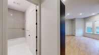 This well-appointed 2-bedroom, 2-bathroom residence at 51 Okner Pkwy in Livingston, NJ offers a thoughtfully designed single-floor layout with modern finishes throughout. Light-toned hardwood flooring flows seamlessly across the living spaces, complementing the clean, neutral color palette.

The open-concept kitchen and living area serves as the heart of the home. The kitchen is outfitted with deep navy cabinetry accented by gold hardware, white quartz countertops, a vertical tile backsplash, and a full suite of stainless steel appliances including a gas range, microwave, dishwasher, and French door refrigerator.

The primary bedroom offers a generous footprint with recessed lighting, while the second bedroom features a bank of three windows that invite natural light and views of the surrounding streetscape. Both rooms connect conveniently to the rest of the unit via clean, well-proportioned hallways.

The bathrooms are finished with elegant marble-look tile flooring, dark vanity cabinetry with white countertops, and a tiled tub-shower combination with chrome fixtures. Additional highlights include three closets with wire shelving systems, a dedicated laundry area, and a utility room, ensuring ample storage and functionality throughout.