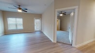 This single-floor residence offers a clean, modern aesthetic with a thoughtful layout designed for comfortable everyday living. The open living area is finished with light hardwood-style flooring and neutral warm-beige walls, creating a bright and welcoming atmosphere. Ceiling fans are installed throughout the main living and bedroom spaces, providing both functionality and a consistent design element. Natural light filters in through multiple windows fitted with horizontal blinds, and a glass-paneled exterior door leads out from the living area, adding to the sense of openness.

The kitchen is well-equipped with grey shaker-style cabinetry, granite-look countertops, a white subway tile backsplash, and a full suite of stainless steel appliances including a range, over-the-range microwave, dishwasher, and a side-by-side refrigerator with an in-door water and ice dispenser. The kitchen also benefits from ample storage, including pantry access doors nearby.

The bedroom features plush wall-to-wall carpeting and a ceiling fan, offering a cozy and quiet retreat. Both bathrooms are finished consistently with grey vanity cabinets, granite-look countertops, framed mirrors, brushed nickel fixtures, and tiled tub-shower combinations with light hardwood-style flooring. The entryway provides a welcoming arrival with a dedicated laundry area conveniently accessible off the hallway.