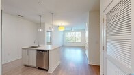 Located at 8000 Essex Point Circle in Orlando, FL 32819, this single-story, 900-square-foot apartment offers a thoughtfully designed layout with 2 bedrooms and 2 bathrooms. The open-concept kitchen serves as a central highlight, featuring white shaker cabinetry, stainless steel appliances including a refrigerator, electric range, and microwave, along with a large center island with a built-in sink, quartz countertops, and stylish pendant lighting. Light wood-style flooring flows throughout the main living and kitchen areas, lending a clean, modern aesthetic. Both bedrooms are carpeted and equipped with ceiling fans, and each benefits from large windows that invite natural light and offer views of surrounding greenery. The primary bedroom measures 140 square feet and includes a dedicated closet with built-in shelving and hanging rods for ample storage. The bathrooms feature wood-look flooring, light wood vanities with quartz countertops, and tub-shower combinations with tile surrounds. Each bedroom is accompanied by its own closet, providing practical storage solutions. The unit's bright, neutral color palette and contemporary finishes create a cohesive and inviting atmosphere throughout.