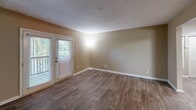 Located in Marietta, Georgia, this single-story, one-bedroom, two-bathroom residence offers a thoughtfully organized layout across a comfortable footprint. The living room features rich, dark hardwood-style flooring and a glass-paneled door that invites natural light and provides access to the outdoors, creating a bright and welcoming atmosphere. Adjacent to the living area, the dining space flows seamlessly into a well-equipped kitchen, which boasts warm honey-toned cabinetry, granite countertops, a peninsula with pendant lighting overhead, and a full suite of white appliances — including a gas range, dishwasher, and refrigerator. The kitchen also features durable wood-look flooring, adding to the cohesive design. The bedroom offers plush carpeting, a window with outdoor greenery views, and a ceiling fan with integrated lighting. A dedicated closet provides practical storage. Both bathrooms are well-appointed; one features a granite-topped vanity with wood cabinetry and hardwood-style flooring, while the other includes a tub-shower combination with elegant marble-style tile surround. Warm beige tones carry throughout the space, lending a consistent and inviting ambiance from room to room.