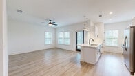 This well-appointed single-story home offers three bedrooms and two bathrooms across a thoughtfully designed floor plan. The interior is defined by a bright, cohesive aesthetic — crisp white walls, light wood-tone luxury vinyl plank flooring, and matte black hardware accents that carry consistently through every room.

The open-concept kitchen and living area serves as the heart of the home. The kitchen features white shaker-style cabinetry, light quartz countertops, a tile backsplash, stainless steel appliances including a range with overhead ventilation, and a peninsula with a black undermount sink and pendant lighting. The adjacent living area is spacious and airy, benefiting from multiple windows dressed with horizontal blinds that invite abundant natural light, complemented by a ceiling fan overhead.

A hallway connects the private quarters, including a generously sized primary bedroom with its own dedicated bathroom. The primary bath includes a glass-enclosed shower with marble-style tile surround. The two additional bedrooms each offer ceiling fans and windows with outdoor views of surrounding greenery. Both bathrooms continue the home's clean, modern design language.

A dedicated laundry room houses a full-size washer and dryer with overhead wire shelving, adding everyday practicality. Two closets provide ample storage. The overall ambiance is bright, clean, and move-in ready.