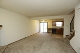 This two-floor home offers a well-organized layout connecting functional living spaces across both levels. The main level features an open-concept living and dining area with plush carpeting, seamlessly connected to a kitchen equipped with warm oak cabinetry, dark granite countertops, black appliances including a dishwasher, range, microwave, and refrigerator, and tile flooring. A sliding glass door off the kitchen provides access to the outdoors, filling the space with natural light. A staircase with a metal railing leads to the upper level, where multiple bedrooms are found, each featuring soft carpet, ceiling fans with light fixtures, generous closet space, and windows with blinds. One bedroom features vaulted ceilings, adding an airy, open feel. The bathrooms are appointed with rich wood vanities, granite countertops, and tile flooring. An attached garage with a full-width overhead door and an automatic opener provides convenient interior access through a dedicated entry area with concrete flooring. A textured ceiling throughout the main living areas and a practical layout make this home a comfortable and functional residence ready for occupancy.