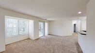Located at 701 College Ln in Salisbury, Maryland, this single-floor residence offers a thoughtfully designed layout that balances comfort and functionality. The spacious living area is bathed in natural light, courtesy of large windows and a sliding glass door that opens onto a private balcony with outdoor views of surrounding greenery. Plush wall-to-wall carpeting runs throughout the living and bedroom areas, contributing to a warm and inviting atmosphere.

The kitchen features a peninsula with dark granite-style countertops, light wood cabinetry offering ample storage, and black appliances including a range and refrigerator. A ceiling fan overhead adds comfort to the adjoining dining or living space. A louvered bi-fold door provides access to a dedicated in-unit laundry area, a convenient and practical feature.

The bedroom is generously sized with soft carpeting and direct access to a full bathroom equipped with a light wood vanity, tile flooring, and a lighted mirror. A second bathroom similarly features tile flooring and a matching wood vanity. The entry hallway is finished with tile flooring and includes additional storage. Throughout, the clean white walls and neutral palette create a bright, move-in ready environment.