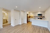 This thoughtfully designed 2-bedroom, 2-bathroom residence offers a clean, modern aesthetic across a single floor. Light hardwood-style flooring flows consistently throughout the space, complementing the neutral, warm-toned walls and crisp white trim found in every room. The open-concept kitchen, dining, and living area serves as the heart of the home, featuring white shaker-style cabinetry, a subway tile backsplash in a muted gray-brown tone, quartz countertops, a kitchen island, and a full suite of stainless steel appliances including a refrigerator, range, microwave, and dishwasher. Recessed lighting illuminates the space efficiently throughout. The primary bedroom is generously sized, bathed in natural light from a window with outdoor views of surrounding greenery, and includes baseboard heating. The second bedroom offers a similarly bright and open feel with its own window. Both bathrooms are finished in clean, classic white with subway tile detailing in the tub-shower surrounds. The unit also includes three closets for ample storage and an in-unit laundry area for added convenience. Wall-mounted air conditioning and baseboard heating provide year-round climate control, completing this move-in-ready residence.