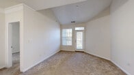 Located at 1200 Harrison Creek Blvd in Petersburg, Virginia, this single-floor residence offers three bedrooms, three bathrooms, and a thoughtfully designed open-concept layout. The combined living, dining, and kitchen area serves as the heart of the home, featuring warm carpet flooring that transitions to hard surface flooring in the kitchen. The kitchen is equipped with stainless steel appliances — including a range, microwave, and refrigerator — complemented by granite-style countertops, white cabinetry, and a peninsula that provides additional prep and dining space. Vaulted ceilings in the living area lend an airy, open feel, while a door with flanking windows fills the space with natural light and provides outdoor access. The primary bedroom is generously sized and includes an en-suite bathroom with a dual-sink vanity featuring granite-style countertops and a soaking tub with white tile surround. Two additional bedrooms offer comfortable accommodations, each served by their own bathroom. Throughout the unit, five closets — including wire-rack systems — provide ample storage. Carpeted hallways and panel-style doors tie the interior together with a clean, consistent aesthetic.