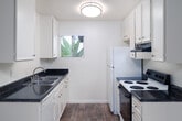 Located at 351 Tamarack Avenue in Carlsbad, California, this one-bedroom, one-bathroom residence offers a well-organized single-level layout designed to maximize functionality. The open-plan living, dining, and kitchen area forms the heart of the home, with soft carpeting underfoot and a ceiling fan overhead providing year-round comfort. A window allows natural light to filter into the space, while a door leads out to a private balcony — ideal for enjoying the Southern California climate.

The kitchen is efficiently designed in a galley style, featuring white cabinetry, dark granite-style countertops, a double-basin sink, and an electric range with oven. Wood-look flooring and ample upper and lower cabinet storage make this kitchen as practical as it is clean in appearance.

The bedroom offers a comfortable footprint, complete with a ceiling fan, carpeted floors, and a full-wall mirrored sliding closet that enhances the sense of space and provides generous storage. The full bathroom is well-appointed with a dark granite-style vanity countertop, white cabinetry, wood-look flooring, a tub/shower combination, and a large mirror above the sink. The overall aesthetic throughout is bright, neutral, and move-in ready.