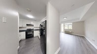 Located at 685 West Broadway in Monticello, NY, this single-floor, one-bedroom, two-bathroom unit offers a clean and modern living environment with a well-designed layout. The open-concept combined living and dining area is bright and inviting, featuring light gray laminate hardwood flooring, neutral warm-toned walls, and a wall-unit HVAC system. Windows allow natural light to flow in, offering outdoor views of the surrounding greenery. A pass-through opening connects the living area to the kitchen, enhancing the sense of openness. The kitchen is well-equipped with crisp white cabinetry, dark granite-style countertops, dark tile flooring, and black appliances including a refrigerator and electric range with overhead ventilation. The spacious primary bedroom continues the light hardwood flooring and provides direct access to a private patio through a glass door. Two bathrooms serve the unit: one features white textured tile walls, a vanity with a dark wood cabinet, and tile flooring, while the second offers a corner soaking tub, large-format light tile walls and floors, and a matching vanity. Additional features include a dedicated laundry area, a utility room, a hallway, and two closets, providing ample storage and functional everyday convenience.