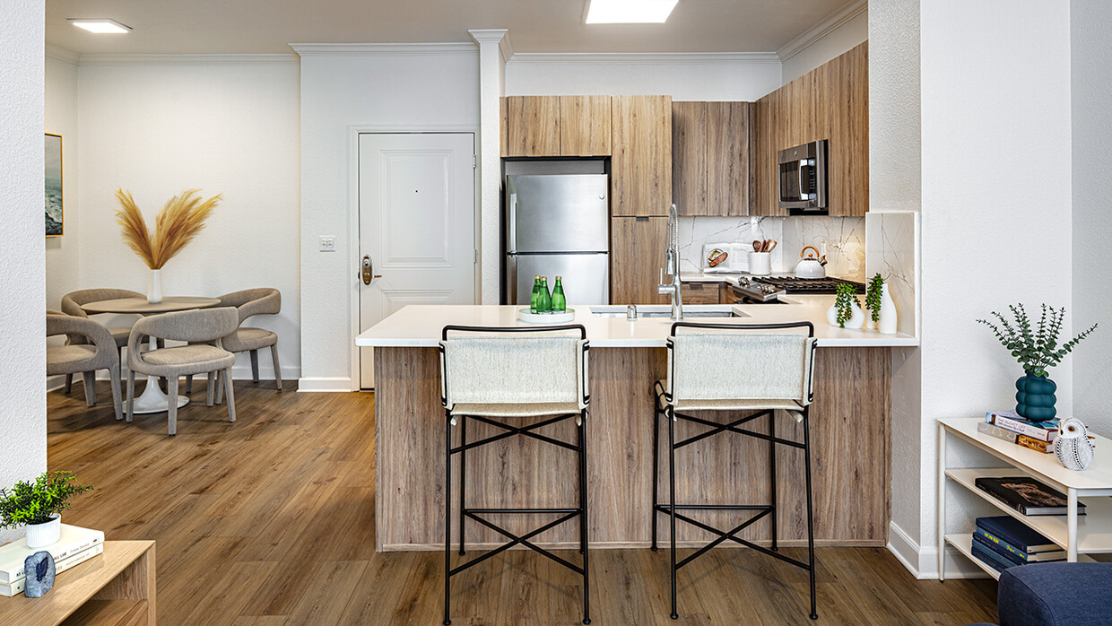 Gourmet kitchen and dining area with stainless steel appliances, quartz countertops and wood-style flooring. - Griffis South Bay