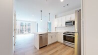 This thoughtfully designed 3-bedroom, 2-bathroom residence at 141 Danbury Rd in Wilton, CT offers a clean, modern aesthetic across a well-organized single-floor layout. The open-concept kitchen is a standout feature, showcasing white shaker cabinetry, a subway tile backsplash, quartz countertops, a center island with a undermount sink, and a full suite of stainless steel appliances including a gas range, microwave, dishwasher, and refrigerator. Pendant lighting above the island adds a warm, contemporary touch, and light wood-style flooring flows seamlessly into the adjoining living area. The living room benefits from large sliding glass doors that invite abundant natural light and provide direct access to a private balcony with views of the surrounding community. The primary bedroom is generously proportioned, with its own balcony access and continued hardwood-style flooring. Additional bedrooms feature plush carpet flooring and large windows. Both bathrooms are finished with neutral tile flooring, white vanities with quartz countertops, and elegant vertical-stacked tile surrounds — one featuring a walk-in glass-enclosed shower, and the other a full soaking tub and shower combination with a backlit mirror. A carpeted hallway connects the bedrooms to the main living spaces, completing this well-appointed home.