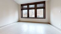 This 440 square foot apartment, located at 1249 Griswold in Detroit, offers a blend of modern convenience and urban living. The single-floor layout maximizes space efficiency, featuring a well-appointed kitchen and a full bathroom. The kitchen boasts rich, dark wood cabinetry contrasting beautifully with stainless steel appliances, including a refrigerator, dishwasher, and over-the-range microwave. A small island provides additional counter space and storage.

The living area is bright and airy, showcasing large windows that frame picturesque views of the surrounding cityscape. These windows, adorned with wood trim, allow ample natural light to flood the space. The room's neutral color palette and tile flooring create a clean, contemporary aesthetic.

The bathroom continues the modern theme with a wood vanity, large mirror, and a glass-enclosed shower. Decorative tile work adds visual interest to the floor. Throughout the apartment, recessed lighting and modern fixtures provide illumination, while the open floor plan allows for easy movement between spaces, making the compact area feel more spacious and accommodating.