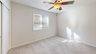 This single-floor residence is designed with a clean, neutral aesthetic throughout, offering a well-organized layout that maximizes functionality across each room. The living area is generously proportioned, featuring plush wall-to-wall carpeting, a textured ceiling, and a large window that allows abundant natural light to fill the space, creating a bright and airy atmosphere.

The kitchen is efficiently laid out with white cabinetry, dark countertops, a stainless steel sink, and light wood-look flooring. Appliances including a refrigerator and range are integrated seamlessly into the cabinetry, making practical use of the available space.

The bedrooms are well-sized, each featuring soft carpeting, ceiling fans with light fixtures, and windows fitted with horizontal blinds that provide both privacy and natural illumination. One bedroom offers direct access to an en-suite bathroom, which includes a vanity with mirror, wood-look flooring, towel hardware, and a separate shower stall. A standout feature of the primary bedroom is the dual sliding-door closets, offering generous storage capacity with built-in hanging rods and shelving.

Throughout the residence, the consistent use of white and neutral tones, along with clean lines and practical finishes, contributes to a cohesive and welcoming interior environment.