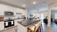 Located at 713 Adelynn Ln in Greensboro, NC, this single-floor, one-bedroom, one-bathroom residence offers a thoughtfully designed open-concept layout finished with light wood-style flooring and a neutral color palette throughout. The kitchen is a standout feature, showcasing crisp white shaker cabinetry with gold hardware, a striking dark quartz island with bar seating, a white subway tile backsplash, stainless steel appliances, and a black undermount sink — all flowing seamlessly into the living area. The living room benefits from natural light streaming through large windows and a glass door, complemented by a ceiling fan overhead. The bedroom is a calm retreat, featuring a ceiling fan, a window with natural light, and ample space for furnishings. The bathroom maintains the home's modern aesthetic with dark quartz countertops, white cabinetry, wood-look flooring, and a shower-tub combination. A dedicated in-unit laundry room with a full-size washer and dryer adds everyday convenience, while a separate closet provides additional storage. Recessed lighting throughout enhances the clean, contemporary ambiance of this efficiently laid-out home.