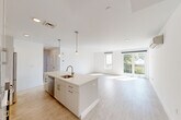 Located at 42 N Beacon Street in Boston's Allston neighborhood, this modern 4-bedroom, 2-bathroom unit offers a thoughtfully designed open-concept layout. Light wood-tone flooring runs throughout, complementing the clean white walls and creating a bright, airy atmosphere.

The kitchen is a standout feature, centered around a large island with a quartz countertop and undermount sink. White shaker cabinetry reaches toward the ceiling, paired with a subway tile backsplash and stainless steel appliances including a refrigerator, range, and microwave. Stylish pendant lights hang above the island, adding a contemporary touch. The kitchen flows seamlessly into a generous living area filled with natural light from large windows and sliding glass doors that open to a private balcony with outdoor views.

The four bedrooms are well-proportioned, each with light flooring and ample natural light. Several rooms feature wall-mounted mini-split units for climate control, and select bedrooms include balcony-facing windows. Each bedroom is served by dedicated closet space. The two bathrooms are cleanly finished, featuring tiled floors, single-sink vanities with quartz countertops, and tub-shower combinations. A dedicated laundry area and entrance hallway complete this well-appointed unit.