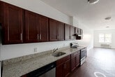 Located at 747 Grand Street in Jersey City, NJ, this well-appointed two-bedroom, two-bathroom residence offers a functional and comfortable single-floor layout. The open-concept living and kitchen area serves as the heart of the home, featuring rich hardwood-style flooring that extends throughout the space. The kitchen is outfitted with deep-toned cabinetry, granite-look countertops, and stainless steel appliances including an electric range, providing an efficient and attractive cooking space that flows seamlessly into the living area. Natural light fills the main living area through a front-facing window, creating a bright and welcoming atmosphere. Both bedrooms are generously proportioned, with the primary bedroom offering a notably spacious layout. Each bedroom features hardwood-style flooring, neutral white walls, individual wall-unit HVAC systems, and windows with views of the surrounding neighborhood streetscape. The two bathrooms are finished with classic subway tile wainscoting, rich wood-toned vanities, white countertops, and large mirrors, lending a clean and timeless aesthetic. A hallway connects the living spaces to the bedrooms and bathrooms, contributing to a well-organized and efficient floor plan throughout.