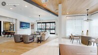 Located on Erwin Road in Durham, North Carolina, this single-floor amenity space is thoughtfully designed to accommodate a variety of social and professional needs. The layout flows seamlessly between distinct functional zones, each characterized by contemporary finishes, curated furnishings, and an abundance of natural light.

The main lounge area features warm light wood flooring, crisp white walls, and exposed steel beams that contrast with a striking wood-paneled ceiling. Large floor-to-ceiling black-framed glass doors and windows offer views of the surrounding outdoor spaces, flooding the interior with natural light. A sculptural multi-arm chandelier anchors the seating arrangement, which includes a neutral sofa, upholstered armchairs, and minimalist side tables.

The dining and social area transitions smoothly from the lounge, showcasing sheer floor-length drapery, pendant lighting, and a mix of round and rectangular tables suited for casual gatherings or communal dining. Concrete planter boxes with moss accents add a natural, organic touch.

A dedicated co-working zone provides a conference table, wall-mounted display, and secondary high-top workstations set against a warm wood-paneled accent wall. Enclosed private meeting rooms with glass walls and doors offer a quieter setting for focused work. Throughout, patterned carpeting, carefully selected artwork, and layered lighting contribute to a polished yet welcoming ambiance.