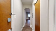 Located at 4111 Walnut Street in Philadelphia's vibrant University City neighborhood, this studio unit offers an efficient and well-designed single-floor layout. The main living area features warm hardwood flooring throughout, neutral gray walls, and crisp white baseboards that create a clean, modern aesthetic. A ceiling fan with integrated lighting anchors the space, providing both comfort and illumination. The kitchen is seamlessly integrated into the living area, equipped with taupe cabinetry, stainless steel appliances including a refrigerator, gas range, and microwave, as well as a dedicated sink area. The transition between the kitchen's tile flooring and the hardwood living space creates a subtle but functional zone distinction. A window fitted with blinds and a wall-mounted air conditioning unit, paired with a traditional cast-iron radiator beneath, ensures year-round climate comfort. The bathroom is clean and functional, finished in white tile with a full bathtub and overhead shower, chrome fixtures, and a toilet. A hallway connects the living area to the bathroom, providing a natural flow through the unit. The overall ambiance is bright, practical, and move-in ready, making it a solid choice in the heart of Philadelphia.