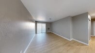 Located at 2255 E Sunset Rd in Las Vegas, Nevada, this single-floor unit offers a clean, modern aesthetic throughout. The open living area is finished with light wood-style luxury vinyl flooring and painted in neutral gray tones, creating a bright and versatile space. A full-width sliding glass door fitted with vertical blinds allows abundant natural light to flow in while providing outdoor access. A wall-mounted HVAC unit and ceiling vents ensure year-round climate control.

The kitchen is outfitted with gray shaker-style cabinetry featuring matte black hardware, white countertops, and stainless steel appliances including a full-size refrigerator. A flush-mount ceiling light and a window with blinds keep the space well-lit and functional.

The bedrooms feature plush carpeting in neutral tones, textured walls, and windows with horizontal blinds. Sliding closet doors provide practical storage solutions. The bathroom is finished with wood-style flooring, white cabinetry with a dark countertop, an undermount sink, matte black fixtures and accessories, and a full tub-shower combination. The consistent neutral color palette and updated finishes throughout give this unit a cohesive and contemporary feel.