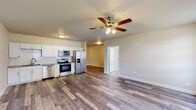 This single-floor unit offers a clean, modern design with warm neutral tones and durable hardwood-style flooring carried consistently throughout. The open-concept kitchen and living area serves as the heart of the space, providing a generous and flexible layout. The kitchen is well-equipped with a full suite of stainless steel appliances — including a French door refrigerator with ice maker, electric range, over-the-range microwave, and dishwasher — all complemented by crisp white shaker cabinetry, a white subway tile backsplash, and a stainless steel sink. A ceiling fan with integrated lighting anchors the living area, enhancing comfort and airflow.

The bedroom areas are bright and spacious, benefiting from natural light admitted through multiple windows. Each room is outfitted with a ceiling fan, and baseboard heating provides an additional climate control option. A dedicated closet with a hanging rod offers practical storage.

The bathroom stands out with a fully tiled walk-in shower featuring a handheld showerhead and grab bar, reflecting a thoughtful, accessible design. Conveniently located within the bathroom, an in-unit washer and dryer adds everyday practicality. Throughout the unit, white trim and neutral wall colors create a cohesive, inviting atmosphere.