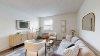 Located at 210 Senate Ave in Camp Hill, Pennsylvania, this thoughtfully designed one-bedroom, one-bathroom residence offers a complete and efficient layout across a single floor. The living room serves as the heart of the home, featuring warm hardwood-style flooring, a textured ceiling, and a large window dressed with blinds that floods the space with natural light. The room provides comfortable space for seating arrangements and is finished with neutral tones that create a calm, welcoming ambiance. The kitchen is well-appointed with white shaker-style cabinetry, light quartz countertops, a white subway tile backsplash, stainless steel appliances, and hardwood-style flooring — offering a clean, modern aesthetic. The bedroom is a serene retreat with plush wall-to-wall carpeting, soft neutral walls, and a window that brings in ample natural light. A full bathroom completes the unit, featuring a tub and shower combination, a white vanity with cabinetry, and wood-look flooring that ties seamlessly to the rest of the home. A hallway and entrance round out the layout, contributing to a practical and organized flow throughout the space.
