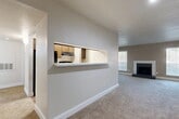 Located at 3636 W Redbird Ln in Dallas, TX, this single-story 2-bedroom, 2-bathroom home offers a functional and comfortable layout. The open living and dining area is anchored by a tile-surround fireplace framed by multiple windows that fill the space with natural light. Plush carpeting runs throughout the living areas, adding warmth underfoot. A distinctive pass-through window with a marble-style countertop ledge connects the kitchen to the living space, creating an open feel while maintaining a defined cooking area. The kitchen features wood-toned cabinetry, black appliances including a range and refrigerator, and wood-look vinyl flooring. Both bedrooms are generously sized, each equipped with a ceiling fan and window treatments. The primary bedroom includes sliding glass door access and ample closet space, with four closets found throughout the home. Both bathrooms are appointed with striking floor-to-ceiling marble-look tile surrounding the tub-shower combinations, accented by built-in niche shelving and brushed nickel fixtures. A dedicated laundry area and a connecting hallway round out the practical layout of this well-appointed Dallas home.