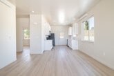 This efficiently designed single-story home in Twin Falls, Idaho, offers a clean, modern aesthetic throughout its two bedrooms and one bathroom. The open-concept living and kitchen area creates a bright, airy feel, anchored by light-toned wood laminate flooring that runs seamlessly throughout the entire home. The kitchen is well-appointed with white shaker-style cabinetry, light countertops, stainless steel appliances including a gas range, microwave, and refrigerator, plus a single-basin sink. Recessed lighting illuminates the space, and a rear door provides convenient exterior access. Both bedrooms are comfortably sized, featuring large sliding windows that invite natural light and offer neighborhood views. Each room includes a wall-mounted HVAC unit for individual climate control. The full bathroom includes a tub-shower combination, a white vanity with a light countertop, and a toilet. The exterior presents a contemporary board-and-batten siding design in a cool gray-blue palette, complemented by a concrete driveway and an attached single-car garage. The home's straightforward, well-maintained layout makes it a practical and comfortable residence in a developing neighborhood setting.