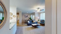 This single-floor residence offers a thoughtfully designed layout that maximizes comfort and functionality throughout. The living room serves as the heart of the home, featuring plush wall-to-wall carpeting, crown molding, a ceiling fan with light fixture, and large windows dressed with sheer curtains that invite an abundance of natural light. The space flows seamlessly into the dining area, which is accented by additional windows and crown molding details, creating a bright and welcoming atmosphere for gatherings.

The galley-style kitchen is efficiently laid out with light wood cabinetry lining both walls, ample counter space, a double sink, and wood-look plank flooring that adds warmth and easy maintenance. White appliances, including a refrigerator, range, microwave, and dishwasher, complete the functional setup.

The bedroom is a serene retreat, finished with soft carpeting, a ceiling fan, and a sliding glass door that opens to a private outdoor patio with views of lush greenery. A hallway with closet access connects to additional areas of the unit.

The bathroom is clean and well-appointed, featuring a tub-shower combination with tiled surround and glass door, a vanity with stone-look countertops, and wood-look plank flooring that ties the space together cohesively.